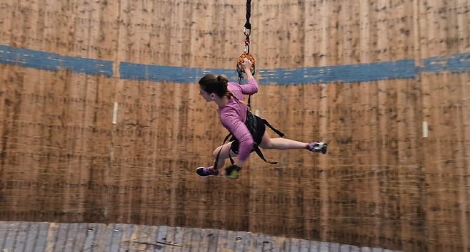 번지 줄을 단 여성이 벽을 타고 달리고 있다. 오토바이로 원통 벽을 타고 달리는 서커스가 있지만 사람은 불가능하다. 하지만 달처럼 중력이 약하면 사람도 수직 벽을 수평으로 달리며 운동할 수 있다. / 이탈리아 밀라노대