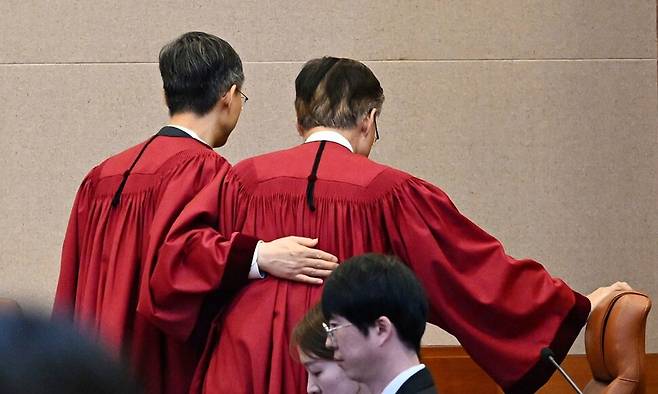 문형배 헌법재판소장 권한대행(왼쪽)이 지난 4일 헌법재판소 대심판정에서 윤석열 전 대통령 탄핵심판 인용 결정을 선고한 뒤 김형두 재판관 등을 두드리며 대심판정을 나서고 있다. 사진공동취재단