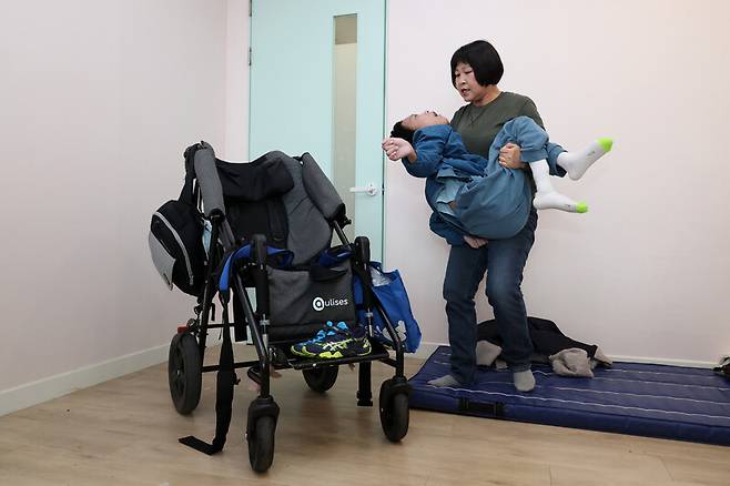 희귀질환 ‘위커 울프 증후군’을 가진 천석현군의 엄마 조묘숙씨가 석현군을 휠체어에 앉히기 위해 안아 들고 있다. 김영원 기자 forever@hani.co.kr