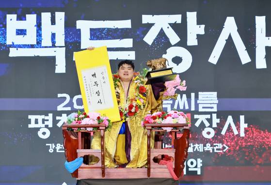 꽃가마에 앉아 백두장사 인증서와 우승 트로피를 들어보이는 서남근. 사진 대한씨름협회