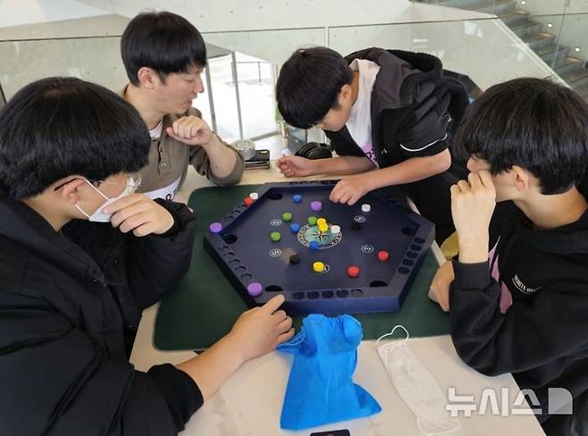 [고양=뉴시스] 청소년들이 모두에게 친숙한 알까기와 포켓볼이 결합된 '스페이스X' 보드게임을 즐기고 있다.(사진=보드아리아협동조합 제공)photo@newsis.com