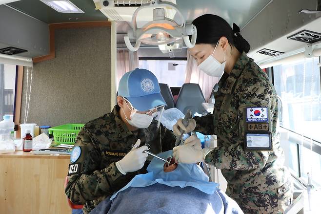 동명부대 치과군의관 손상현 대위와 치위생부사관 박규선 중사가 이동형치과버스에서 치료를 하고 있다. [합참 제공]