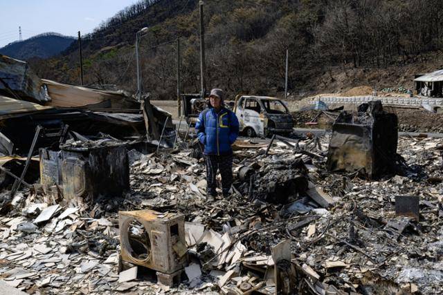 의성 점곡면 사촌1리의 과수 농민 최기철씨가 잿더미가 된 집터에 서 있다. 이번 산불로 주택과 농업용 창고, 저온저장고, 화물차, 각종 농기계, 관개 시설 등이 소실됐다. 최씨는 "일상의, 농업의 기반을 모두 잃었다"며 "사람이 다치지 않아 다행이고, 살아 있으면 살아지는 것 아니겠나"라고 말했다.