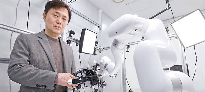 서울대 컴퓨터연구소 패러덱스 설비 공간에서 서진욱 서울대 컴퓨터연구소장이 로봇 손과 악수하고 있다. 이곳에서는 인간의 움직임을 여러 대의 카메라로 촬영해 동작을 모사하는 인공지능(AI) 모델을 개발하고 이를 로봇으로 재현하는 기술을 연구한다.   /이솔 기자