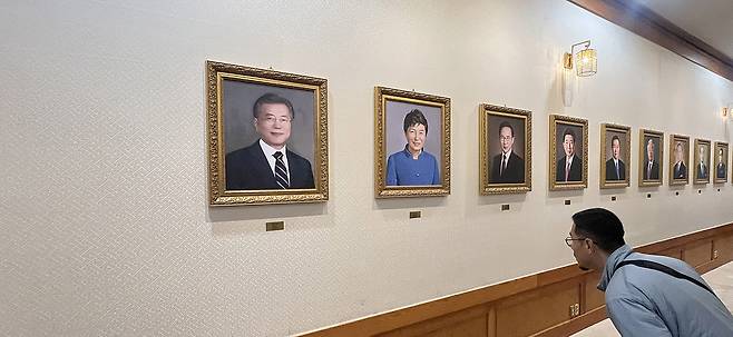 <청와대 본관에 걸린 역대 대통령 초상화> 윤석열 전 대통령의 탄핵 선고 이틀 후인 6일 서울 종로구 청와대 본관에 걸려 있는 역대 대통령의 초상화를 한 시민이 살펴보고 있다. 성동훈 기자