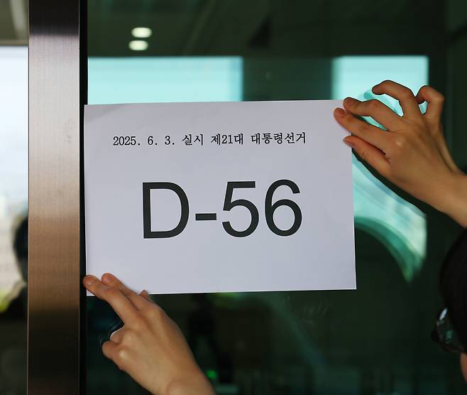 <다음은 ‘시민을 지키는’ 대통령으로> 윤석열 전 대통령 파면으로 치러지는 21대 대통령 선거일이 오는 6월 3일로 확정된 8일 경기 과천시 중앙선거관리위원회에서 한 직원이 56일 앞으로 다가온 선거일을 표시한 문구를 출입문에 붙이고 있다. 정지윤 선임기자