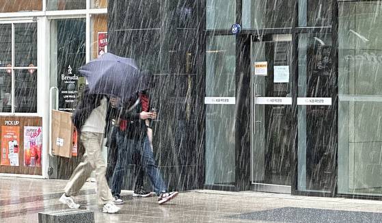 People hurry through falling snow near Jogyesa Temple in Jongno District, central Seoul, on April 13. [NEWS1]