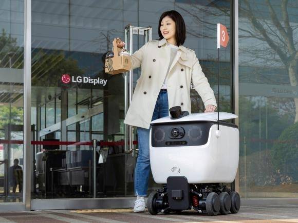 LG디스플레이가 경기 파주 사업장에 도입한 인공지능(AI) 기반 자율주행 로봇으로부터 한 직원이 배달된 음료를 수령하는 모습. 이 로봇은 파주 사업장에 입점한 커피 매장에서부터 사무·공장동 등 임직원이 근무하는 건물 입구까지 음료 배달을 해준다. LG디스플레이 제공