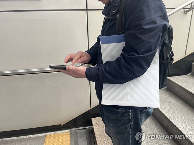 '다음엔 어디로 가야 하나' (서울=연합뉴스) 오인균 인턴기자 = 지난 2일 노인 택배원이 의뢰인을 만나 물건을 전달받고 다음 행선지를 휴대전화로 검색하고 있다. 2025.04.13