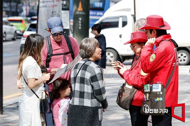 서울 중구 명동을 찾은 외국인 관광객들이 관광안내 도우미에게 길을 묻고 있다. 강진형 기자