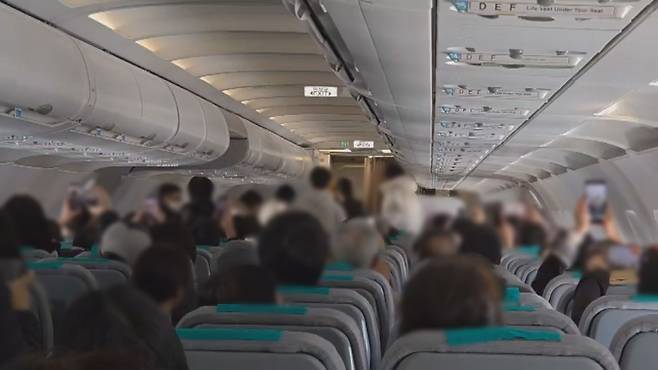 제주발 여객기 안에서 비상문 강제 개방이 상황이 벌어진 뒤 승객들이 휴대전화로 현장을 촬영하는 모습 (사진, 시청자 제공)