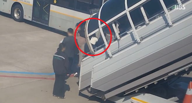 항공기 비상문을 강제 개방한 30대 여성 A 씨가 공항경찰대에 인계되는 모습 (사진, 시청자 제공)