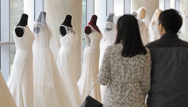 예비부부들에게 ‘스드메(스튜디오 촬영·드레스·메이크업)’ 서비스의 높은 비용은 큰 부담으로 다가온다. 사진은 한 웨딩 박람회에서 웨딩드레스를 둘러보고 있는 예비부부. /뉴스1