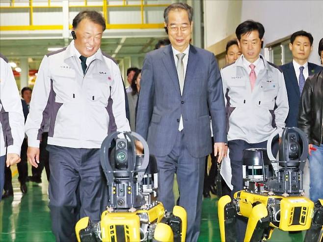 < 로봇개 따라 걷는 韓대행 > 한덕수 대통령 권한대행이 15일 기아 오토랜드 광주공장을 방문해 로봇개 ‘스폿’을 따라 걷고 있다. 왼쪽은 최준영 기아 사장. 국무총리실 제공