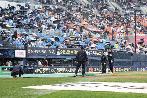 13일 서울 송파구 잠실야구장에서 열린 2025 프로야구 두산 베어스와 LG 트윈스의 경기, 6회초 우천으로 경기가 중단돼 구단 관계자가 방수포를 덮고 있다. 뉴시스