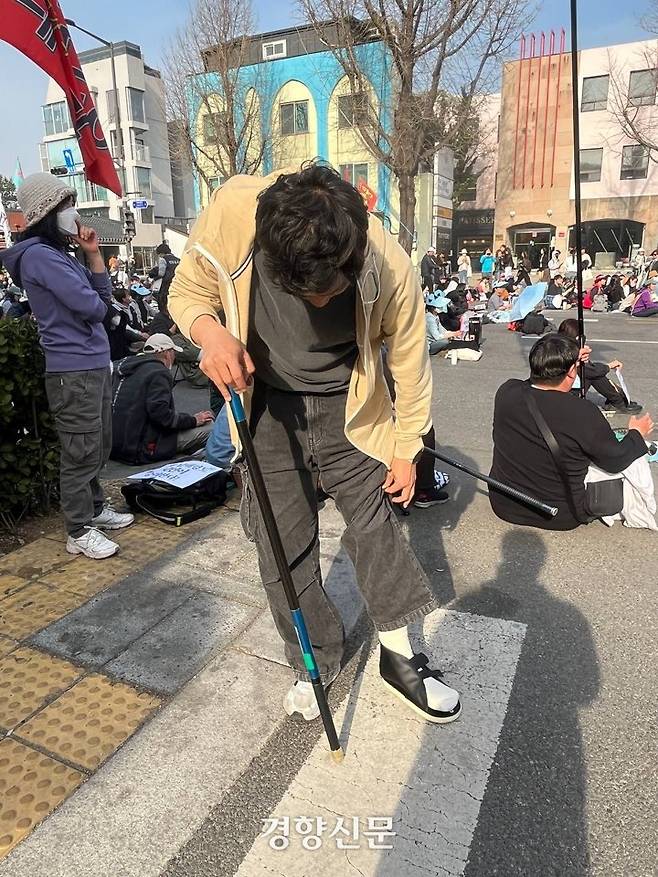 지난 3월26일 서울 종로구 경복궁역 인근에서  박태훈 진보당 대학생위원회 준비위원장이 왼쪽 발목을 응급처치한 후 깃대를 목발 삼아 서 있다. 박 위원장 제공