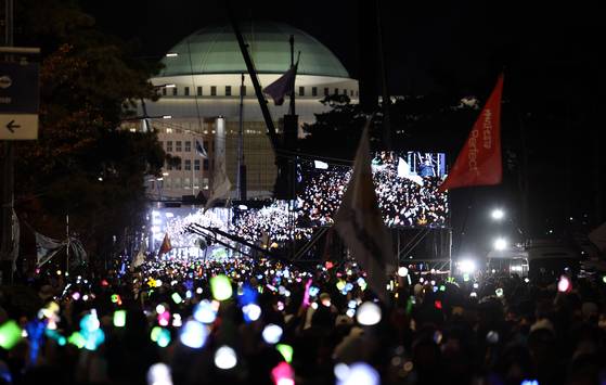 윤석열 대통령 탄핵소추안이 가결된 지난해 12월 14일 서울 여의도 국회 앞에서 열린 촛불집회에 참석한 시민들이 응원봉과 촛불을 켠 채 환호하고 있다. 연합뉴스