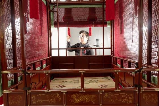 Park Hyun-ju, director of the Hanbok Technology Promotion Institute, inspects a palanquin in an office in Goyang, Gyeonggi, on April 2. [JUN MIN-KYU]