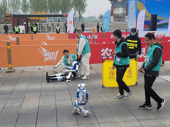 휴머노이드 로봇&nbsp;‘환환’이&nbsp;19일 중국 베이징에서 열린 세계 첫 휴머노이드 마라톤에서 쓰러져 주저앉아 있는 가운데&nbsp;뒤이어 출발한 ‘샤오쥐런’이 환환을 따라잡고 있다.&nbsp; &nbsp;&nbsp;베이징=이우중 특파원