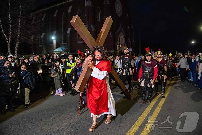 18일(현지시간) 미국 매사추세츠주 첼시에서 열린 성금요일 행사에서 십자가를 든 예수 행렬이 이동하고 있다. ⓒ AFP=뉴스1