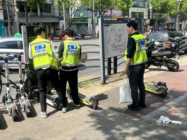 무단방치돼 통행을 가로막는 PM을 통행로와 이격시켜놓은 후 계고문을 붙이고 있는 대구시·북구청 합동 단속인원들의 모습. 김정원 기자