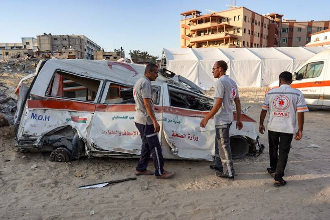 팔레스타인 구급대원들이 가자지구 남부 칸 유니스에서 이스라엘과 하마스 간 분쟁이 계속되는 가운데 폭격 현장에서 파괴된 구급차를 조사하고 있다.(사진=AFP)
