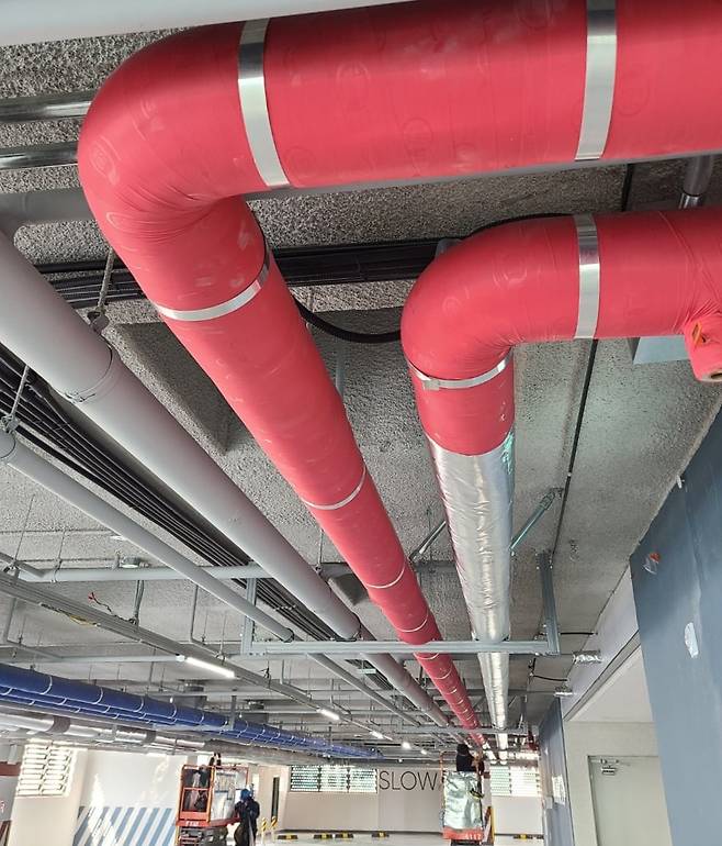 경기도 시흥의 ‘시흥 신천역 해링턴 타워 709’ 건설 현장에서 작업자가 기존 붉은색 배관 보온재 위로 은색 필름 형태의 화재 확산 방지용 제품을 덧씌우고 있다./대승산업