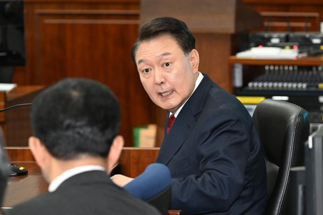 윤석열 전 대통령이 21일 서울 서초동 서울중앙지법에서 열린 내란 우두머리 혐의 형사재판 두 번째 공판에 출석해 피고인석에 앉아 변호인에게 이야기하고 있다. 뉴시스