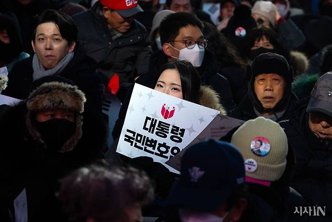 2월13일 서울 청계광장에서 열린 대통령국민변호인단 출범식에 참여한 한 참가자가 손피켓을 들고 있다. ⓒ시사IN 이명익