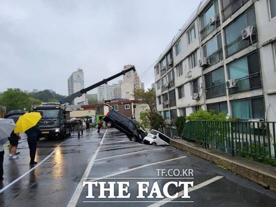 22일 오후 1시 9분쯤 경기 남양주시 화도읍 창현리에 위치한 한 아파트 앞 주차장이 붕괴된 가운데 소방당국이 사고로 인해 파손된 차량을 인양하는 모습을 주민들이 걱정스럽게 지켜보고 있다. /경기북부소방재난본부