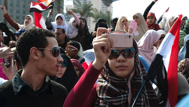스마트폰 통해 퍼진 '아랍의 봄' - '아랍의 봄(아랍권 민주화 운동)'이 이어지던 2011년 이집트 카이로에서 시위에 참여한 한 여성이 스마트폰을 들고 현장을 촬영하고 있다. 당시 억눌린 개인의 목소리를 전하며 주목받았던 소셜미디어는 최근 정치 권력의 선전 도구가 됐다는 비판을 받고 있다.