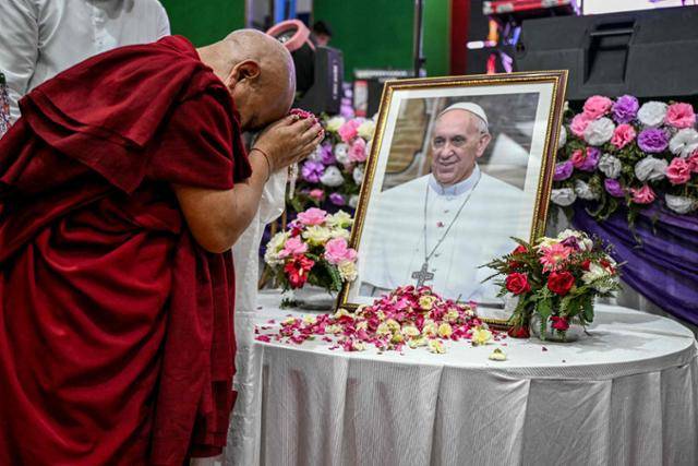 인도 뉴델리의 한 사찰에서 열린 프란치스코 교황의 조문 행사에서 한 승려가 교황의 초상화 앞에서 경의를 표하며 꽃잎을 뿌리고 있다. 뉴델리=AFP 연합뉴스