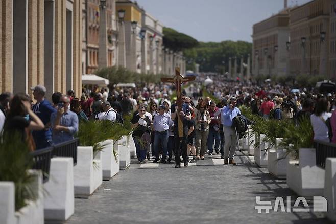 [바티칸시국=AP/뉴시스] 프란치스코 교황이 선종한 21일 바티칸의 성 베드로 광장에서 신자들이 십자가를 들고 이동하고 있다. 2025.04.21.