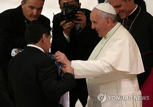 마라도나 만나는 프란치스코 교황 (바티칸 로이터=연합뉴스 자료사진) 2014년 9월 1일 바티칸의 바오로 6세 홀에서 축구 스타 디에고 마라도나(왼쪽)로부터 아르헨티나 국가대표팀 셔츠를 선물받는 프란치스코 교황의 모습. 2025.4.22.