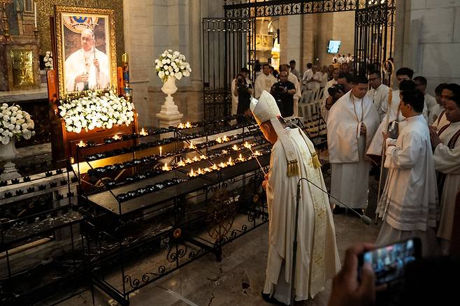 22일 필리핀 호세 아드빈쿨라 추기경이 교황 선종 후 진혼미사 중 마닐라 대성당 예배당에 전시된 프란치스코 교황 성상 앞에서 촛불을 밝히고 있다./로이터 연합뉴스