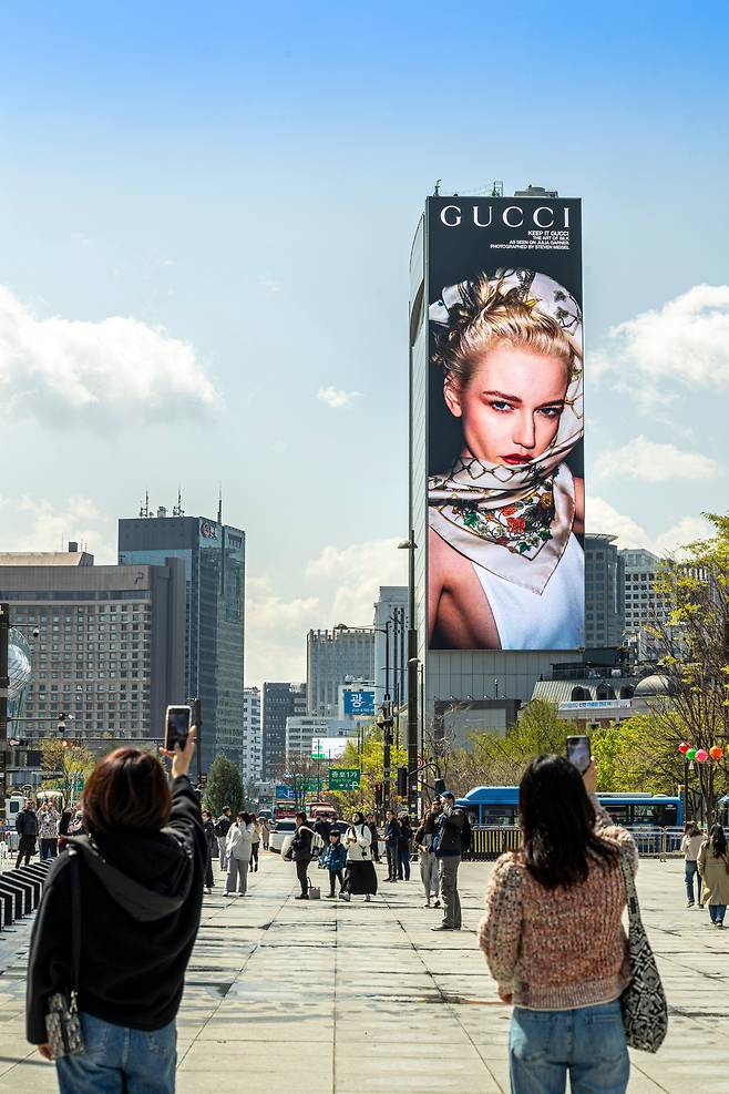 서울 광화문광장에서 코리아나호텔 외벽 디지털 옥외광고판을 촬영하는 여성들. /이신영 영상미디어 기자