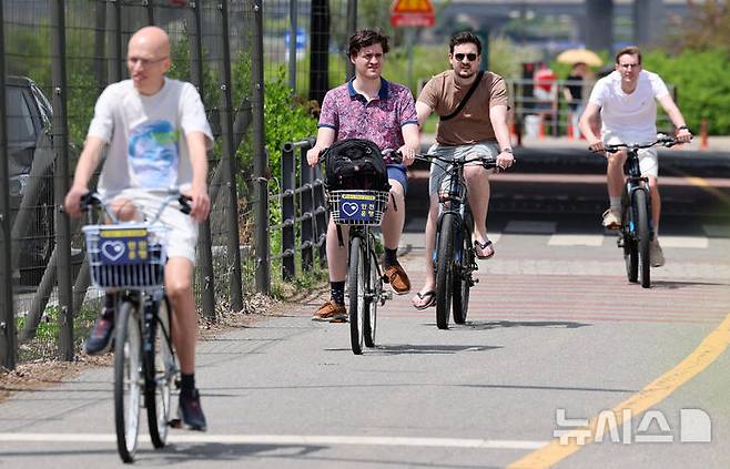 [서울=뉴시스] 이영환 기자 = 서울의 낮기온이 24도까지 오르며 초여름 날씨를 보인 23일 오후 서울 영등포구 여의도한강공원에서 반팔을 입은 외국인들이 자전거를 타고 있다. 2025.04.23. 20hwan@newsis.com