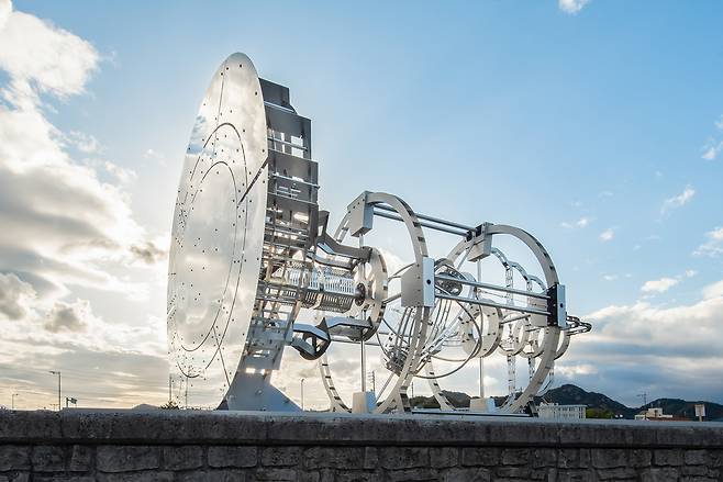 작품 전면의 대형 타원형 거울은 작품이 설치된 물리적 공간과 그 너머를 연결한다. 작품 앞에 서면 대형 거울로 인해 그 뒤의 구조는 보이지 않고 가려진다.&nbsp;관람자는 실제 풍경과 그것을 반사하는 거울 사이, 끝없이 이어지며 변화하는 풍경이라는 비현실적 공간에 놓이게 된다.&nbsp;