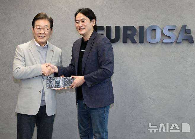 [서울=뉴시스] 국회사진기자단 = 제21대 대통령 선거 출마를 선언한 이재명(왼쪽) 더불어민주당 전 대표가 14일 서울 강남구 퓨리오사AI에서 백준호 퓨리오사AI 대표와 NPU칩을 듣고 기념촬여하고 있다. 2025.04.14. photo@newsis.com