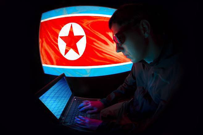 북한 인공기 배경으로 컴퓨터 해커가 작업 중이다.(사진=게티이미지)