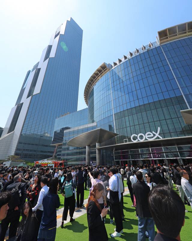 25일 건물내 입점한 식당에서 화재가 발생한 서울 강남구 코엑스 앞에 긴급 대피한 시민들이 모여 있다. [연합뉴스]