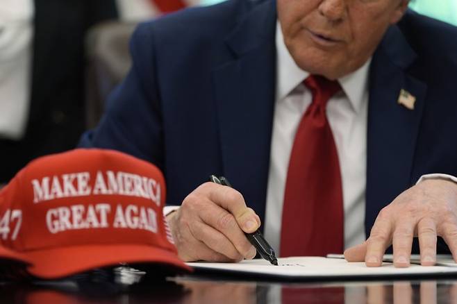 도널드 트럼프 미국 대통령이 지난 23일(현지시간) 미 워싱턴 백악관 집무실에서 한 행정명령에 서명하고 있다.AP연합뉴스