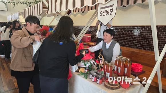 24일 찾은 경기 이천 시몬스 테라스 '파머스 마켓' 오건농장 부스에서 한 방문객이 토마토잼을 구매하고 있다. [사진=진광찬 기자]