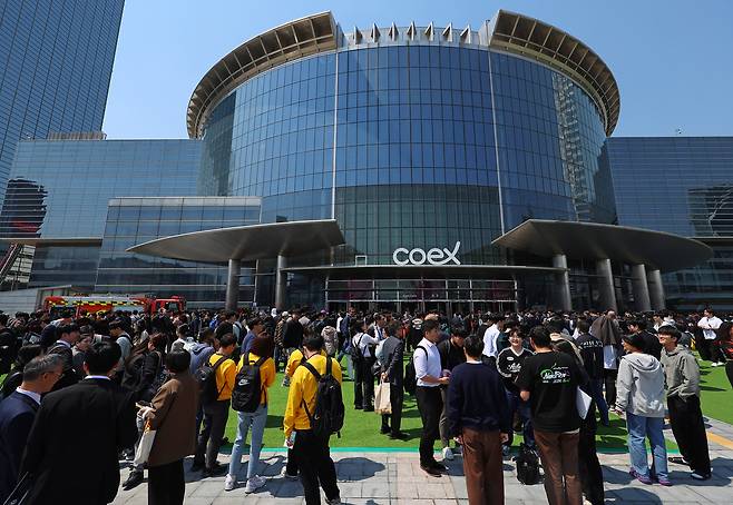 People who were inside Seoul's Coex convention center Friday morning evacuate to outside the building. (Yonhap)