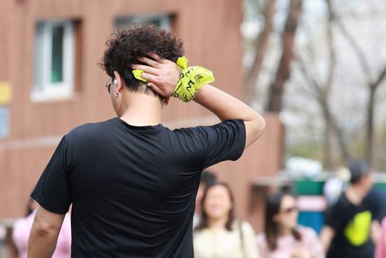 A visitor to N Seoul Tower, a landmark Seoul building with a transmission antenna sitting atop Namsan, is seen wiping away sweat as Seoul experiences fluctuating hot-cold weather conditions on April 17. [YONHAP]