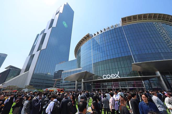 25일 건물내 입점한 식당에서 화재가 발생한 서울 강남구 코엑스 앞에 긴급 대피한 시민들이 모여 있다. [연합]