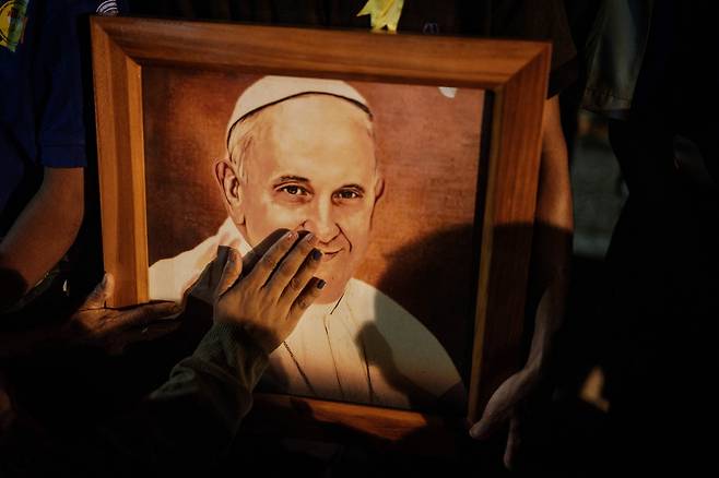 4월 25일(현지시각) 동티모르 딜리의 라르고 데 레시데레 성모 마리아 동상 발치에서 열린 추모 미사에서 신자들이 프란치스코 교황을 기리는 초상화를 만지고 있다. / AFP 연합뉴스