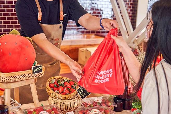 '2025 파머스 마켓'에 참여한 지역 농가 '라우딸기'에서 한 소비자가 딸기를 사고 있다.ⓒ시몬스