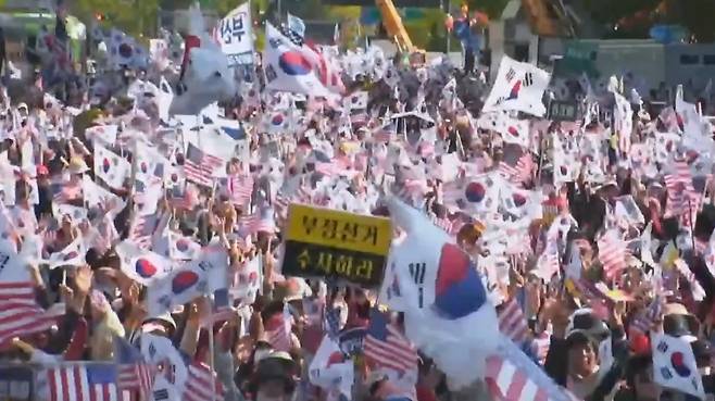 26일 광화문 광장을 가득 메운 참가자들이 태극기와 성조기를 흔들며 집회를 이어가고 있다. (‘전광훈TV‘ 캡처)