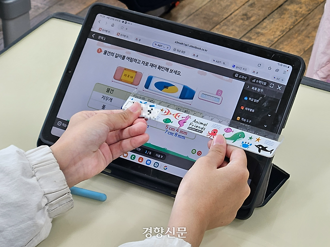 한 학생이 AI 디지털교과서에 탑재된 자를 사용하는 방법을 몰라 실물 자를 태블릿PC에 대고 있다. 김송이 기자